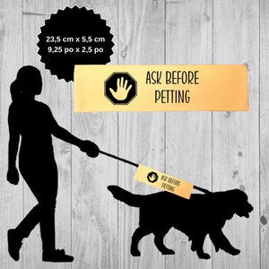 May include: A black silhouette of a person walking a dog on a lead. The dog is wearing a yellow tag that says "Ask Before Petting".