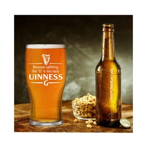 Op de afbeelding: Een pintglas gevuld met bier, met de tekst "Uinness G" en een harp-logo. Daarnaast een bruine bierfles, een kleine kom pinda's en een flesdop. Het glas heeft de tekst "Because splitting the 'G' is too easy".