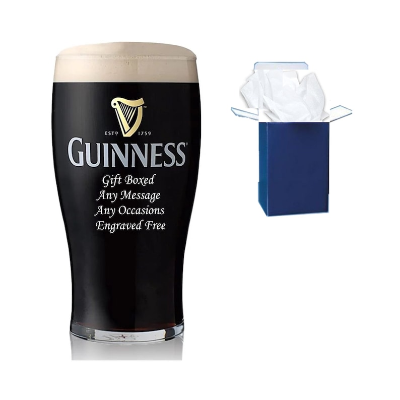 May include: A black pint glass with the Guinness logo and the text "Gift Boxed Any Message Any Occasions Engraved Free". The glass is filled with a dark liquid and is sitting on a white surface. The glass is in a blue gift box with white tissue paper.