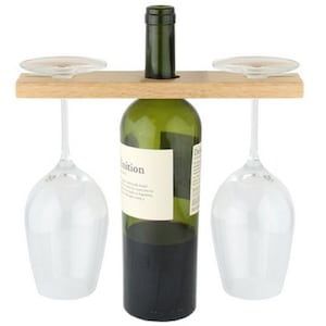 May include: Wooden wine bottle and glass holder with two wine glasses hanging from the sides. The bottle holder has a slot for a bottle of wine and two grooves for the wine glasses.