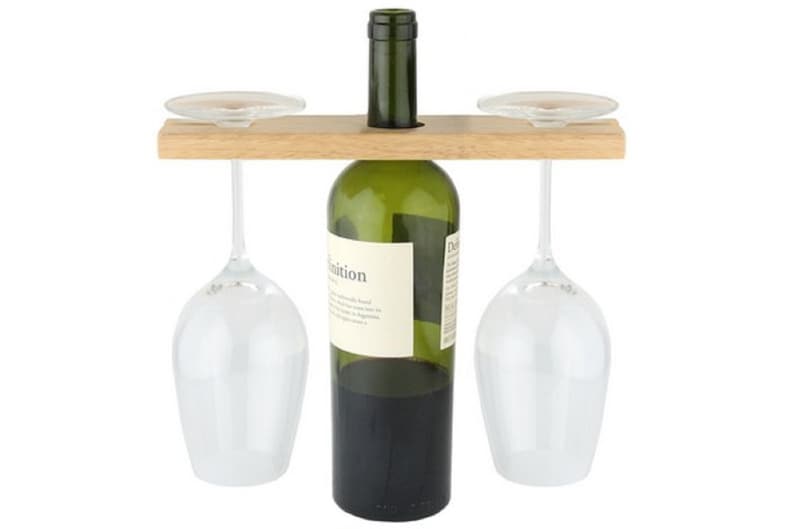 May include: Wooden wine bottle and glass holder with two wine glasses hanging from the sides. The bottle holder has a slot for a bottle of wine and two grooves for the wine glasses.
