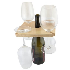 May include: Wooden wine bottle and glass holder with four glasses hanging from the sides. The holder is made of natural wood and has a square shape.