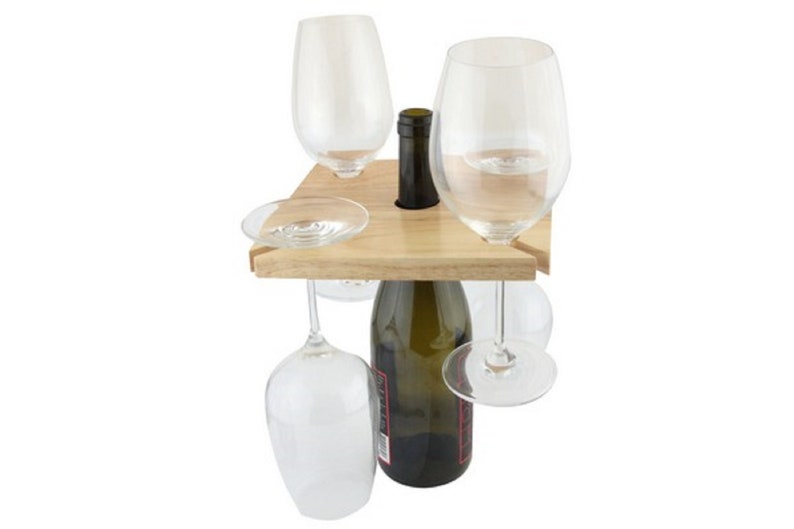 May include: Wooden wine bottle and glass holder with four glasses hanging from the sides. The holder is made of natural wood and has a square shape.