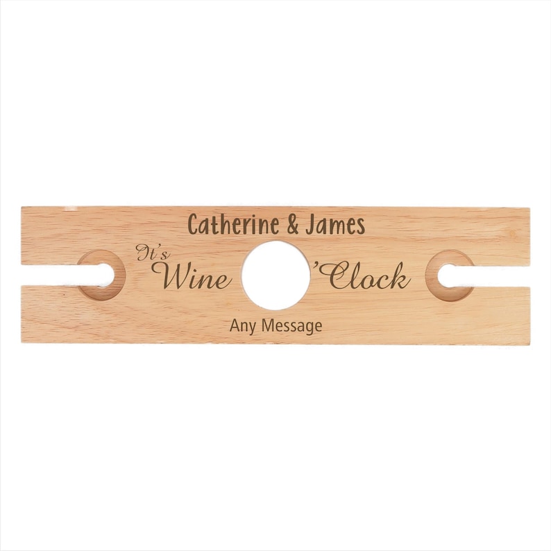 May include: Wooden wine bottle holder with two slots for glasses. It says "It's Wine 'Clock" and "Catherine & James" with space for a personalized message.