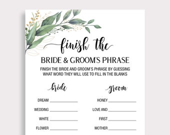 May include: A white card with the text "finish the BRIDE & GROOM'S PHRASE" in black script. The card includes fill-in-the-blank prompts for a wedding game, with floral and gold leaf accents. The game is designed for a bridal shower.