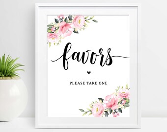 May include: A framed white sign featuring the word "favours" in elegant black script, a small heart, and the text "PLEASE TAKE ONE." Floral arrangements with pink roses and green leaves decorate the corners.