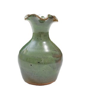 Puede incluir: Un jarrón de cerámica hecho a mano con un borde con volantes. El jarrón tiene un esmalte verde con detalles marrones y una base marrón rojizo. Es un artículo decorativo para el hogar.