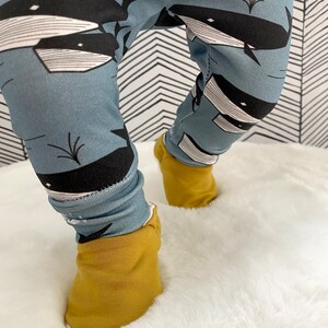 Op de afbeelding: Een blauwe baby leggings met een walvisprint. De leggings hebben gele omslagmanchetten.