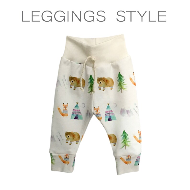 May include: White leggings with a brown bear, green tree, and orange fox print. The leggings have a white elastic waistband and a drawstring.