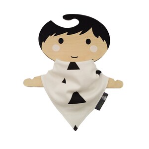 Puede incluir: Un pañuelo blanco con patrones de triángulos negros en una percha de madera con forma de muñeca. La muñeca tiene el pelo negro y una cara sonriente.