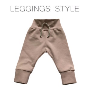 May include: A pair of light pink leggings with a drawstring waistband. The leggings have a cuffed hem.