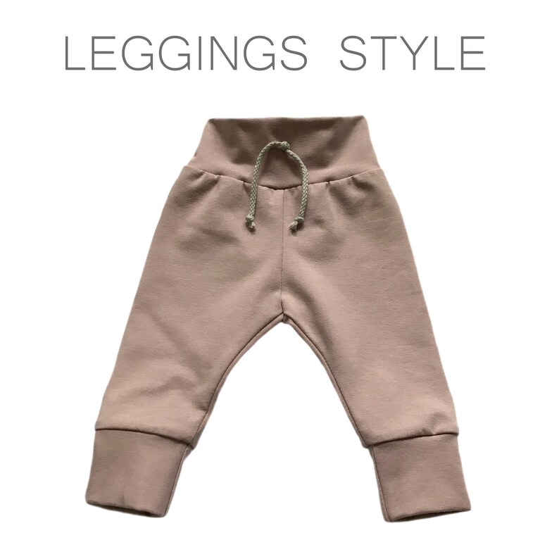 May include: A pair of light pink leggings with a drawstring waistband. The leggings have a cuffed hem.