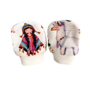 May include: A pair of white baby mittens with a colorful print of a llama and a girl wearing a poncho. The mittens have a white cuff.