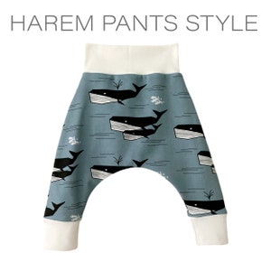 Op de afbeelding: Blauwe harem broek met een witte walvis en vis print. De broek heeft een witte elastische tailleband en manchetten.
