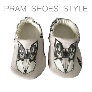 May include: A pair of baby shoes with a geometric fox design in black and white on a light gray background. The shoes have a white elastic band around the top.