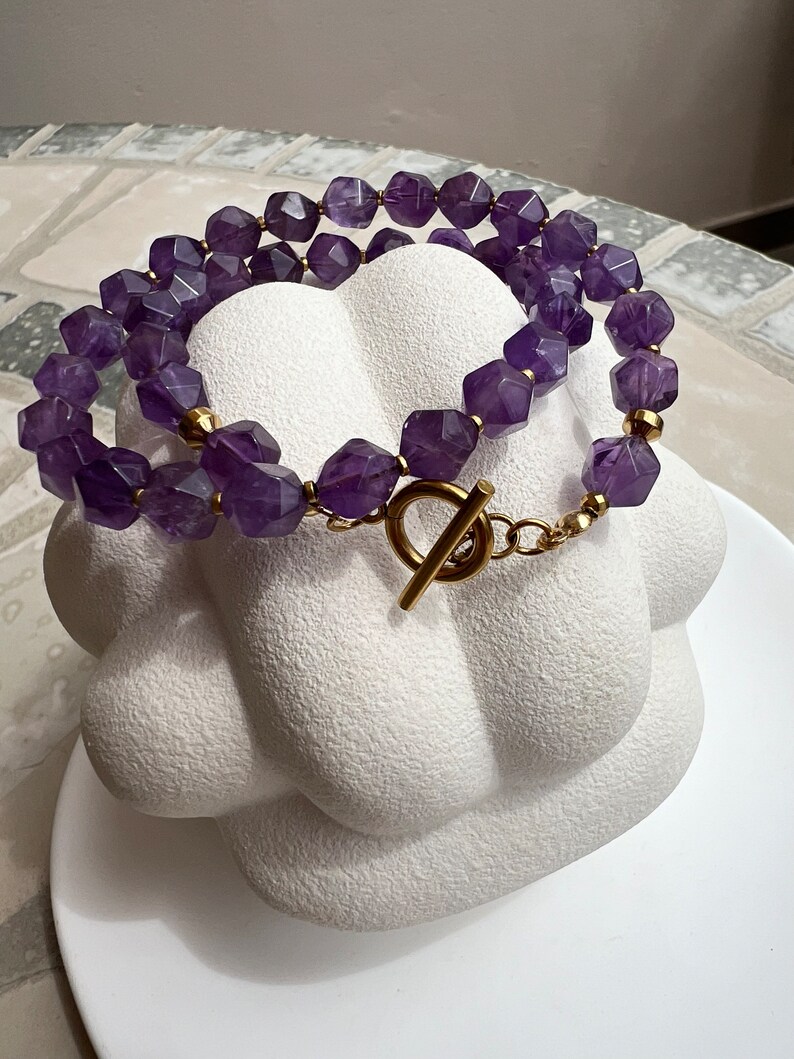 May include: A double-strand necklace made with faceted amethyst beads and a gold-tone toggle clasp.