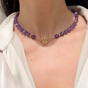 May include: A gold necklace with a toggle clasp and purple amethyst beads.