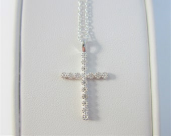 May include: A silver chain necklace with a small diamond cross pendant.