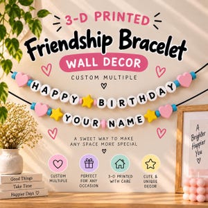 May include: A 3-D printed friendship bracelet wall decor featuring two black strings with white letter beads spelling HAPPY BIRTHDAY and YOUR NAME, interspersed with pink heart beads, yellow star beads, and blue spacer beads on a light background.