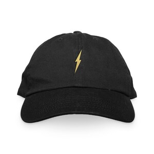 May include: A black baseball cap with a gold lightning bolt embroidered on the front.