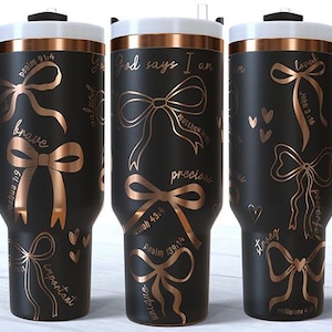 Puede incluir: Vaso t&eacute;rmico negro con borde y asa blancos, con dise&ntilde;os de lazos color cobre y texto inspirador. El vaso incluye frases como "brave" y "loved" con vers&iacute;culos b&iacute;blicos. Tiene un asa negra y una pajita.