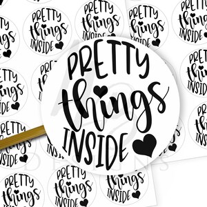May include: A sheet of white sticker labels with black text that reads "Pretty things inside" with a small heart symbol. The stickers are arranged in a grid pattern.