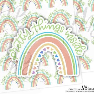 May include: A sticker with a rainbow design and the text "pretty things inside". The rainbow is made up of five colors: green, blue, yellow, orange, and pink. The rainbow is outlined in white and has small hearts in the center.