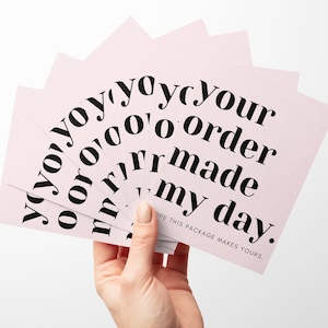 May include: Pink cards with the text "yoyoyoyoyour 0'000 order yoyoru oor rrmade my day." The text is in black and the cards are fanned out.