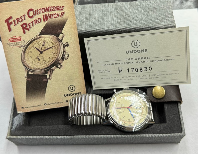 May include: A hybrid mechanical quartz chronograph watch with a cream-colored face, silver case, and black leather band. The watch is displayed in a gray box with a promotional card that reads "First Customizable Retro Watch!!". The watch case size is 40mm.