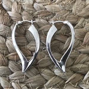 May include: A pair of silver hoop earrings with a unique, curved, teardrop shape.