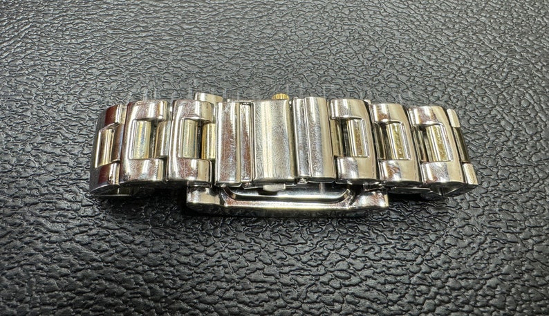 K&ouml;nnte beinhalten: Ein silbernes und goldenes Armband mit einem Verschluss. Das Armband besteht aus Metallgliedern.