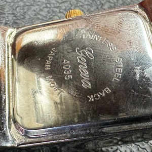K&ouml;nnte beinhalten: Nahaufnahme der R&uuml;ckseite einer silbernen Uhr mit der Gravur "Back Steel Stainless Geneva 4035 Japan Movt".