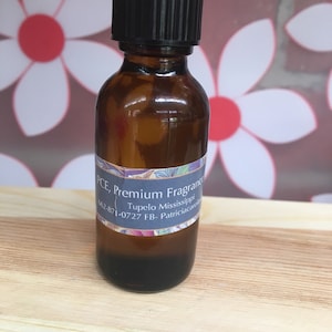May include: A small brown glass bottle with a black cap. The bottle has a white label with the text "PCE, Premium Fragrance, Tupelo Mississippi, 662-871-0727 FB- Patriciacarole".