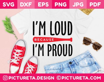 May include: A white t-shirt featuring the black text I'M LOUD and I'M PROUD separated by a red baseball bat graphic with the word BECAUSE in white text. The shirt is displayed with red sneakers, blue denim shorts, and sunglasses.