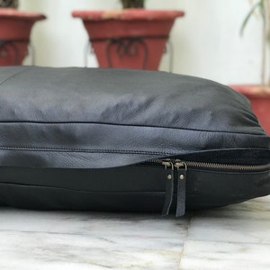 May include: Black leather dog bed with a zipper closure. The bed is rectangular and has a quilted design.