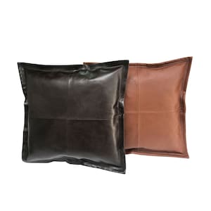May include: Two square leather throw pillows, one brown and one black. The pillows have a stitched design with four panels.