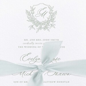 May include: A wedding invitation with a light blue ribbon tied in a bow. The invitation features a floral monogram with the initials "EM" and the text "MR. AND MRS. JOHN SMITH cordially invite you to THE WEDDING OF Evelyn Rose and Michael Shawn SON OF MR. MATTHEW DONOVAN."
