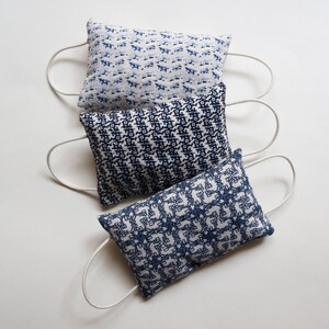 May include: Three blue and white patterned fabric pouches with white drawstrings. The pouches are stacked on top of each other.