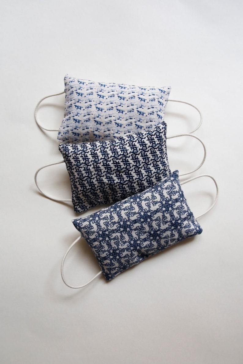 May include: Three blue and white patterned fabric pouches with white drawstrings. The pouches are stacked on top of each other.