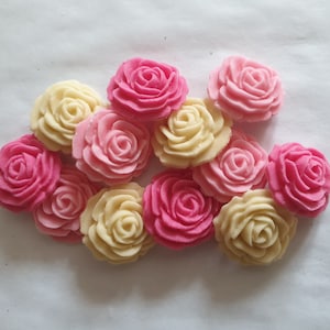 May include: A collection of 12 sugar paste roses in pink and white. The roses are ideal for decorating cakes, cupcakes, and other desserts.