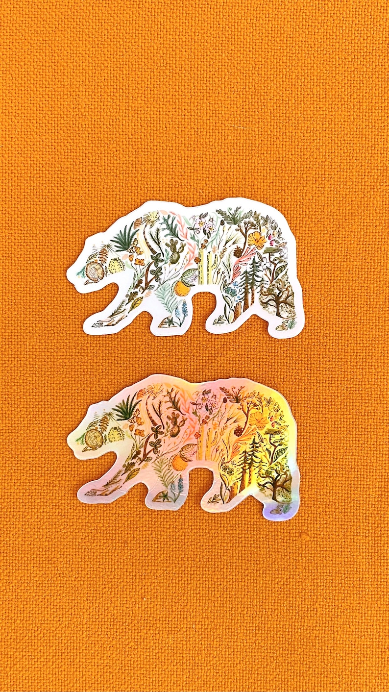 May include: Two bear-shaped stickers with a floral pattern. The top sticker is white with a green, yellow, and brown floral pattern. The bottom sticker is iridescent with a pink, orange, and yellow floral pattern.