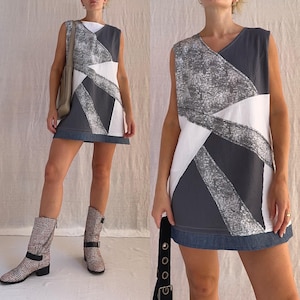 May include: A sleeveless dress with a geometric pattern in white, grey, and blue. The dress has a denim hem and is made of a soft, comfortable fabric.