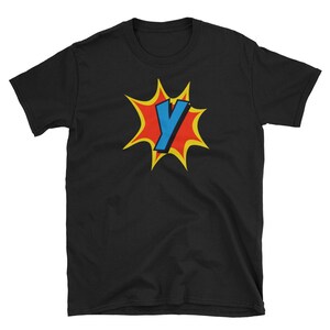 Op de afbeelding: Zwart T-shirt met een rode en gele explosie in comic-stijl met een blauwe letter Y in het midden.
