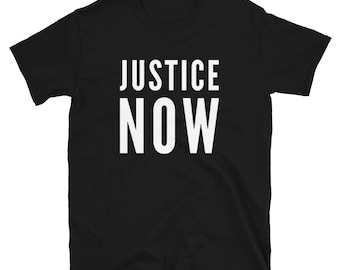 以下が含まれることがあります： 白文字で「JUSTICE NOW」と書かれた黒いTシャツです。