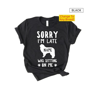 May include: A black t-shirt with the text "Sorry I'm Late [Name] Was Sitting On Me" and a white silhouette of a dog. The text "Change To Any Breed!" is in a yellow box.