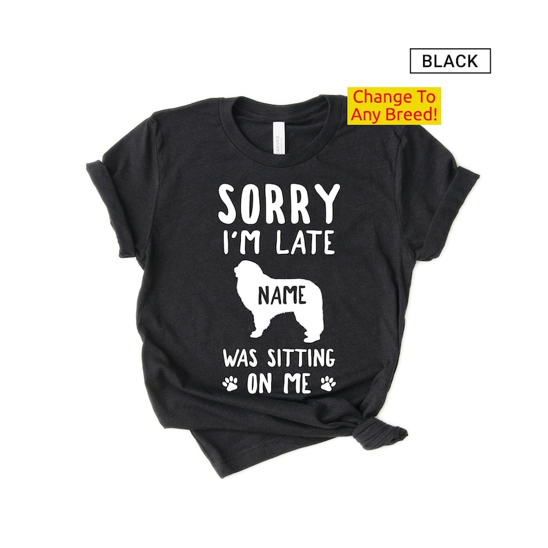 May include: A black t-shirt with the text "Sorry I'm Late [Name] Was Sitting On Me" and a white silhouette of a dog. The text "Change To Any Breed!" is in a yellow box.