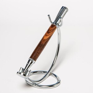May include: A wooden pen with a silver metal top and bottom, resting on a silver metal stand.