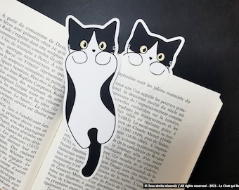May include: Two black and white cat bookmarks with yellow eyes. The cats are smiling and have a white patch on their chest. The bookmarks are on a book with text about art.