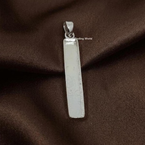 Könnte beinhalten: Ein rechteckiger Anhänger in Silber mit einer Schlaufe oben. Der Anhänger hat eine glatte, reflektierende Oberfläche und befindet sich vor einem braunen Hintergrund. Der Text "Finding World" ist auf dem Anhänger zu sehen.