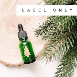 May include: A green glass dropper bottle with a black cap and a gold tree decal. The bottle is on a wooden surface with pine branches. The text "LABEL ONLY" is at the top.